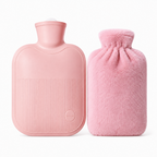 A light pink hot water bottle with a ribbed front and a matching fluffy pink cover beside it, photographed on a clean white background.