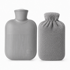 A gray hot water bottle with a ribbed textured front and a screw-top neck, shown next to a matching gray plush drawstring hot water bag on a clean white background.